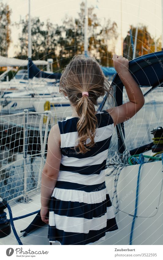 Girl in a striped dress on a sailboat looking at the harbour girl Child Sailboat Ponytail Dress Stripe Harbour Railing Sailing Summer Stand Dream Infancy yacht