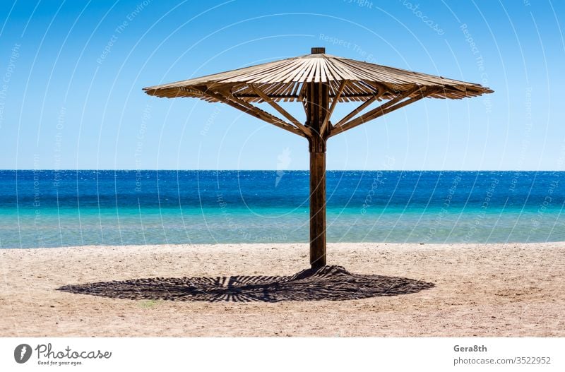 one wooden beach umbrella on the sand on the beach against the blue water of the Red Sea in Egypt Dahab South Sinai background beach background day empty