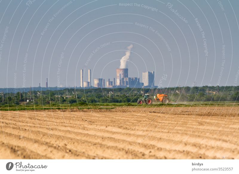 Lignite power station Niederaussem, in the foreground a farmer who applies pesticides to his field. Lignite power generation and conventional agriculture, responsible for climate change and pollution of the environment