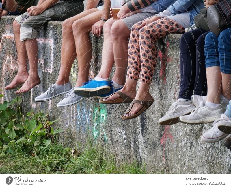 young people chill out on the wall and let their feet dangle foot Legs Wall (barrier) Sit Dangle Many festival Barefoot youthful Summer free time