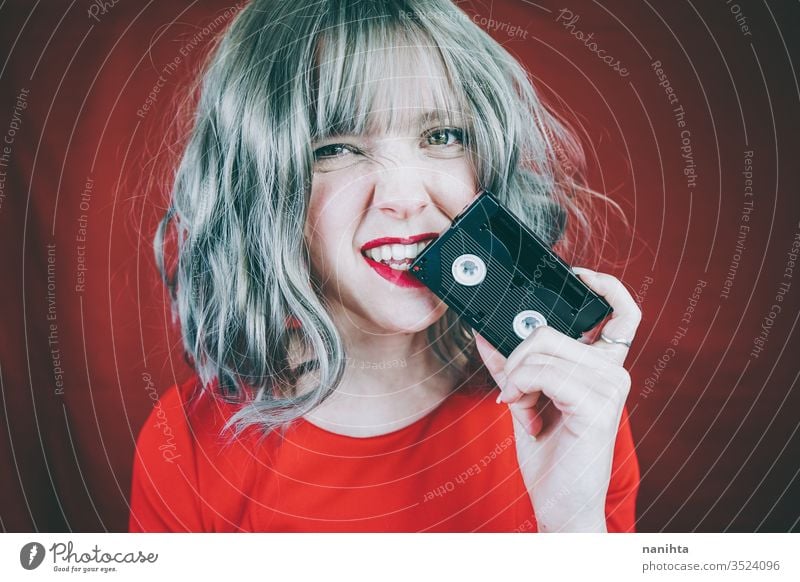 Artistic portrait with a model covering her face with a retro video tape vintage cassette red woman sexy pretty music culture 90s 80s decade old concept idea