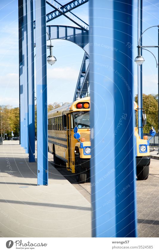 American school bus between blue pillars of an arched bridge School bus US school bus Arched bridge piers Bridge pier Blue travel Driving Colour photo