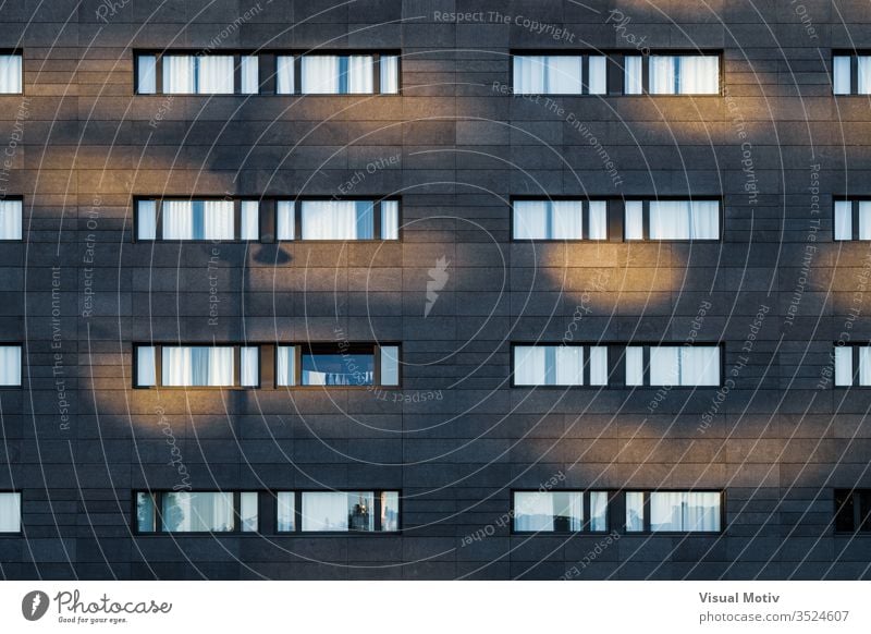 Afternoon light over the black facade of an urban building with long horizontal windows rows structure Architecture abstract building facade urban facade color