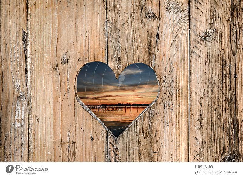 sawn out heart in a wooden board wall with view to the sunset at the lake Heart boards Sawn Sunset Vista Wooden board wall Wooden boards cute structure