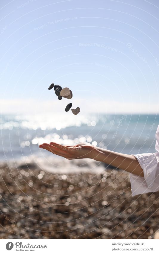 female hand throws a pebble in her hand against the background of the blue sky, beach and sea. place for text. girl young nature summer beauty travel people