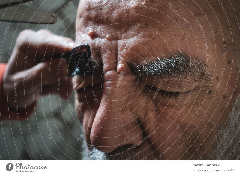 Elderly Getting His Eyebrow Trimmed in his Bathroom man head beard hair facial hair person face elder old people elderly forehead adult portrait human bald