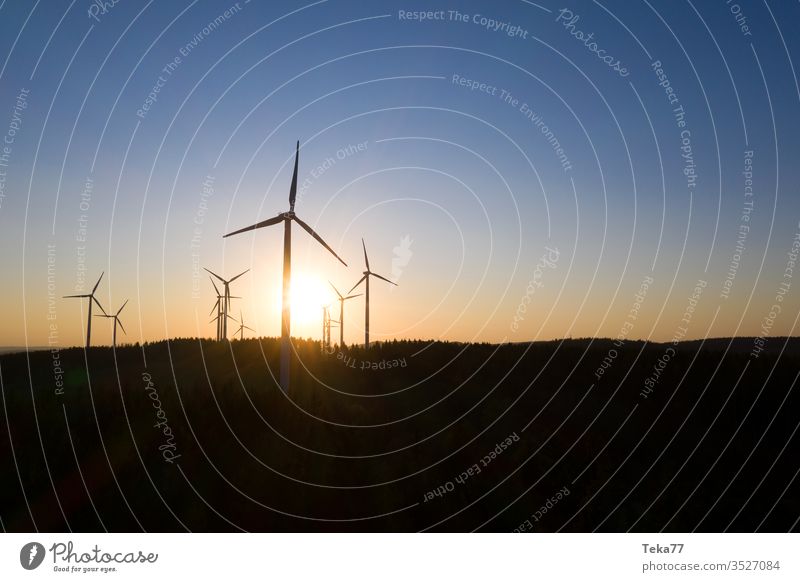 some wind wheels in an evening sundown air electricity energy forest hills from above green electricity green energy landscape needle forest panorama turbine