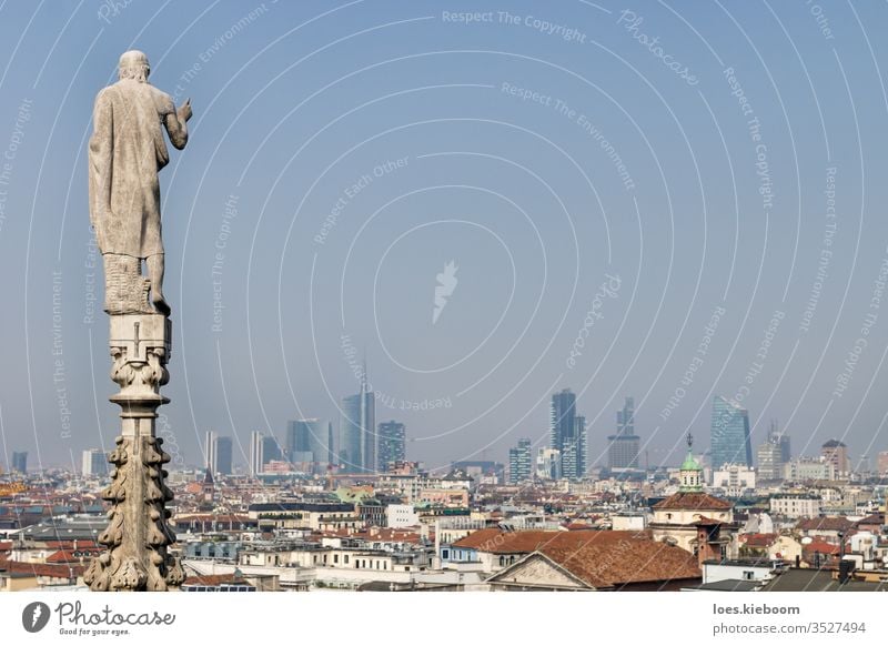 Statue of the dome looking over the modern cityscape of Milan, Italy on a sunny day cathedral italy architecture milan aerial panoramic view urban skyline