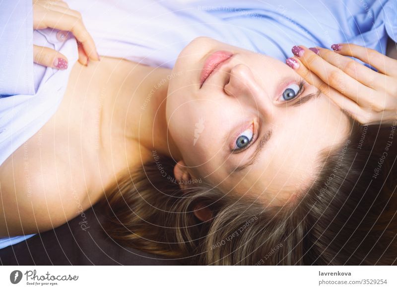 Closeup of young beautiful woman in blue lying in bed. Natural beauty. Selective focus. Film style romantic relaxation spa face body health treatment selective