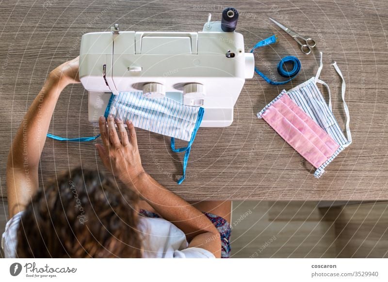 Woman making face masks with a sewing machine at home 2019-ncov above close-up cloth clothes clothing combat corona corona virus coronavirus cotton covid