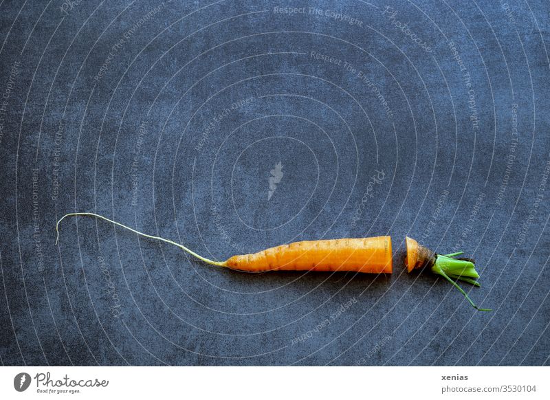 Carrot with cut and missing piece lies crosswise on dark worktop carrot carrot green Food Vegetable Organic produce Nutrition Vegetarian diet Orange conceit