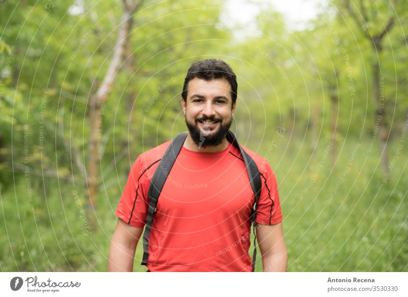 Attractive bearded man walks through the woods hiking with his backpack hike forest outdoors happy nature walking arab middle eastern tree one man only 30s 40s