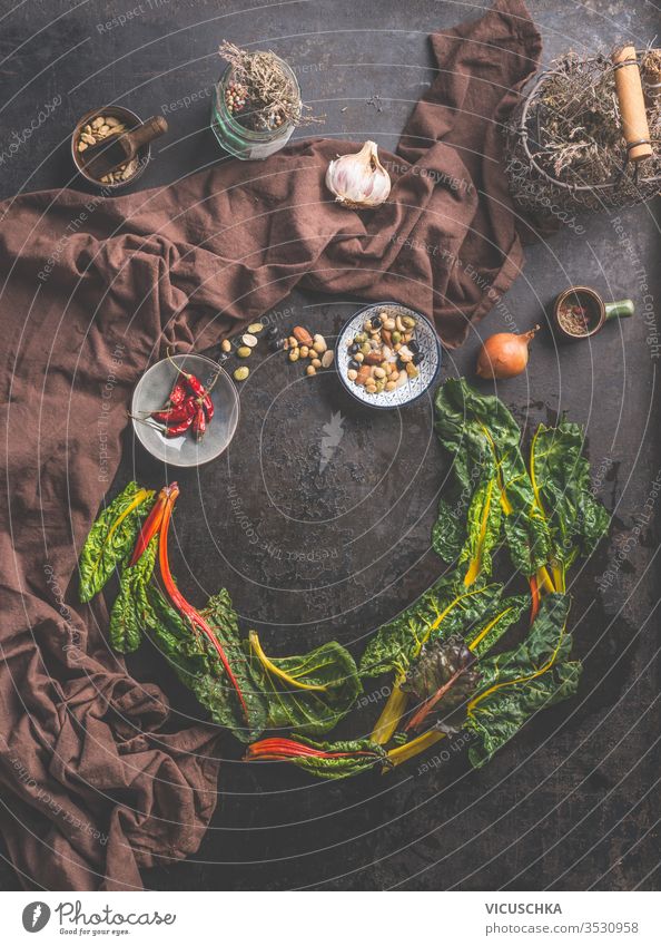 Food background with fresh colorful chard leaves on dark rustic table  background. Home cuisine. food herbs spices top view circle frame country style clean