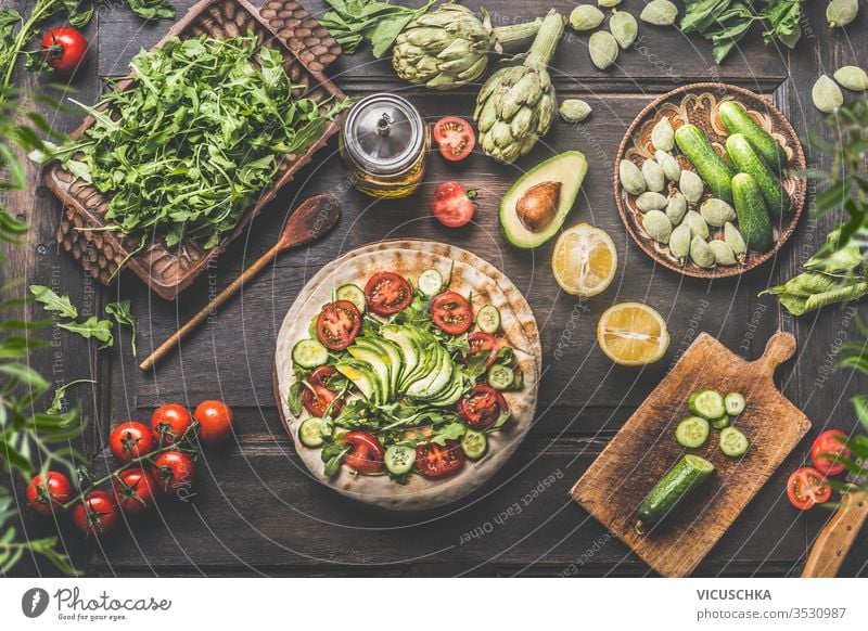 Healthy vegetarian lunch ingredients. Tortilla wraps with fresh vegetables, avocado , olives oil and lemon on rustic wooden kitchen table , top view. Cooking preparation. Vegan food.