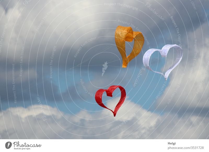 Dreiklang | three paper kites in the shape of hearts flying in the wind in front of a blue-grey sky Heart Paper Flying Sky Clouds Love Colour photo Deserted Day