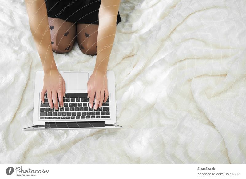 Young woman in her bed is checking her laptop computer cup home young girl using white beautiful technology morning business socks person typing female internet