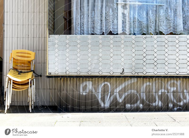 corona thoughts |Yellow chairs chained to a fifties retro wall are waiting to be used. The coronavirus corona crisis coronavirus SARS-CoV-2 tiles Graffiti leap