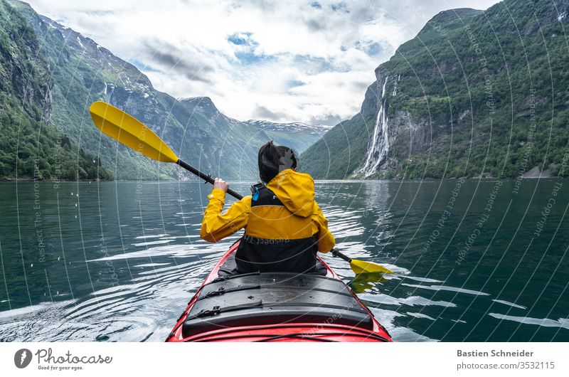 Woman paddling in Geirangerfjord, Norway Mountain Landscape Fjord Environment Colour photo Waterfall Beautiful weather Sunlight Clouds Exterior shot Deserted