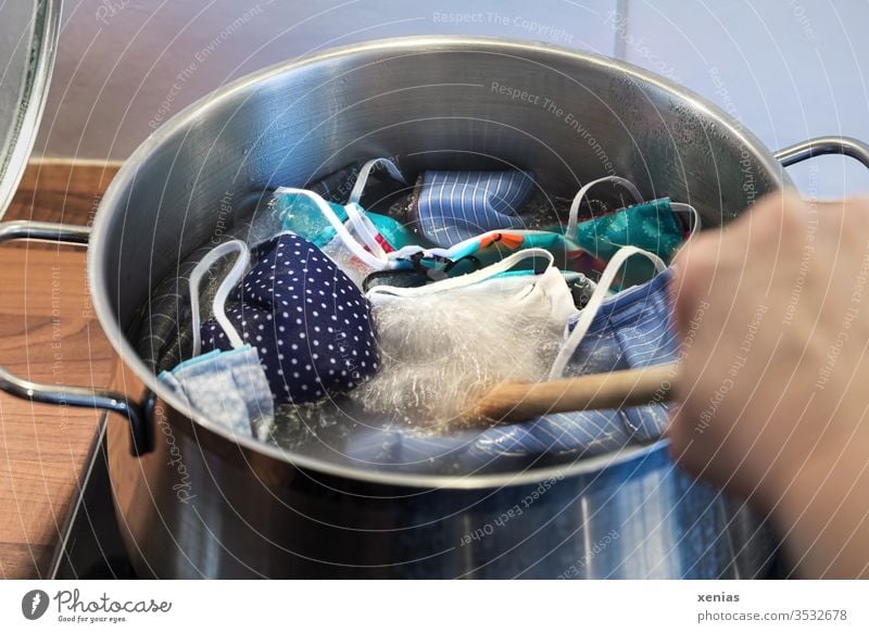 many colorful self sewn masks are boiled out in the cooking pot in the kitchen on the stove and stirred with the cooking spoon before I distribute them to the dear family / corona thoughts