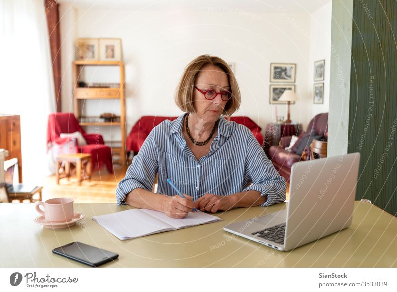 Middle age senior woman working at home using computer female laptop mature people one house person lifestyle desk drink glasses attractive relax technology job