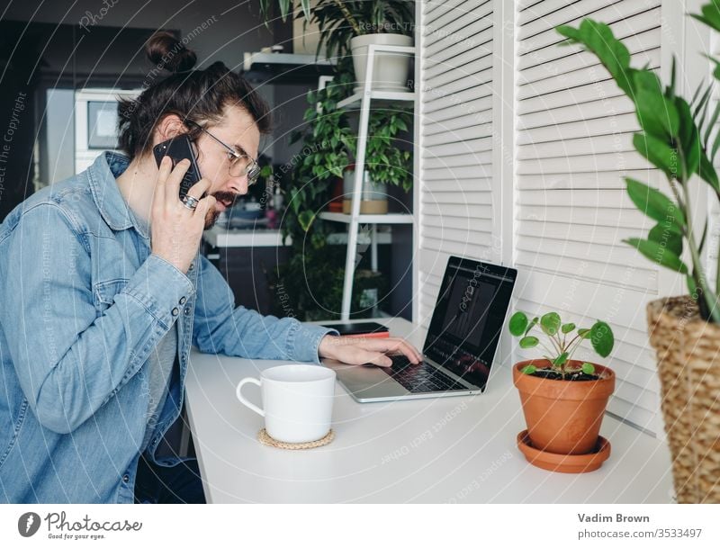 Young man with beard sitting on the chair and using laptop. Freelance work from home in quarantine concept video chat online shopping using technology