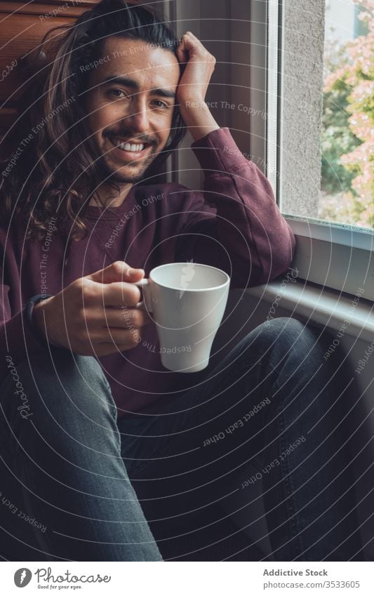 Adult male with mug looking out window man drink stay at home rest coronavirus covid-19 morning cozy hot casual adult beard long hair beverage relax lifestyle