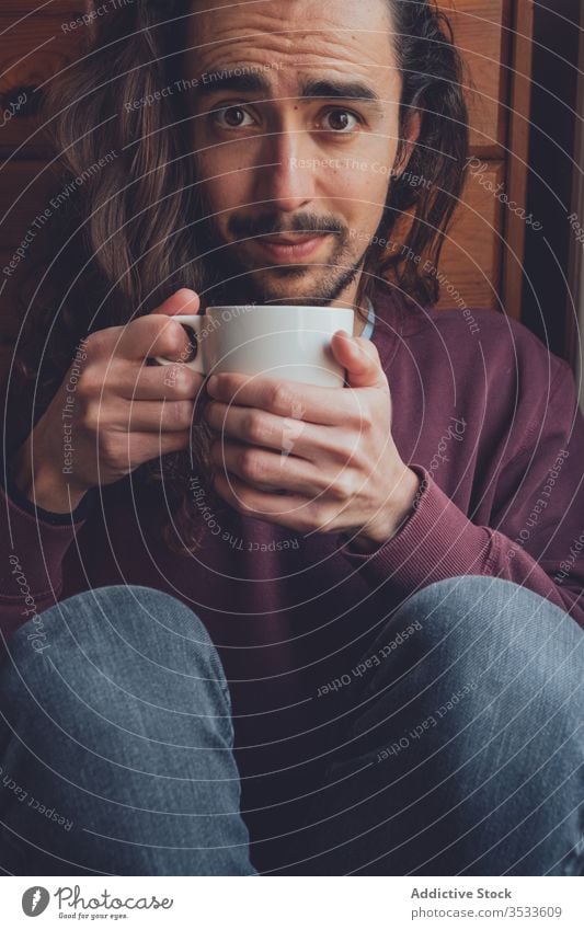 Bearded man resting with hot beverage drink home coronavirus stay at home covid-19 cozy mug mood adult room male relax tea coffee cup comfort long hair beard