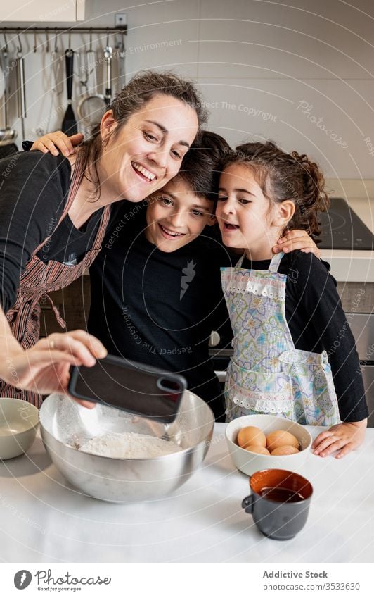 Mother taking selfie with kids during pastry preparation mother children cook home kitchen smartphone mobile phone smile happy love together cozy girl boy woman