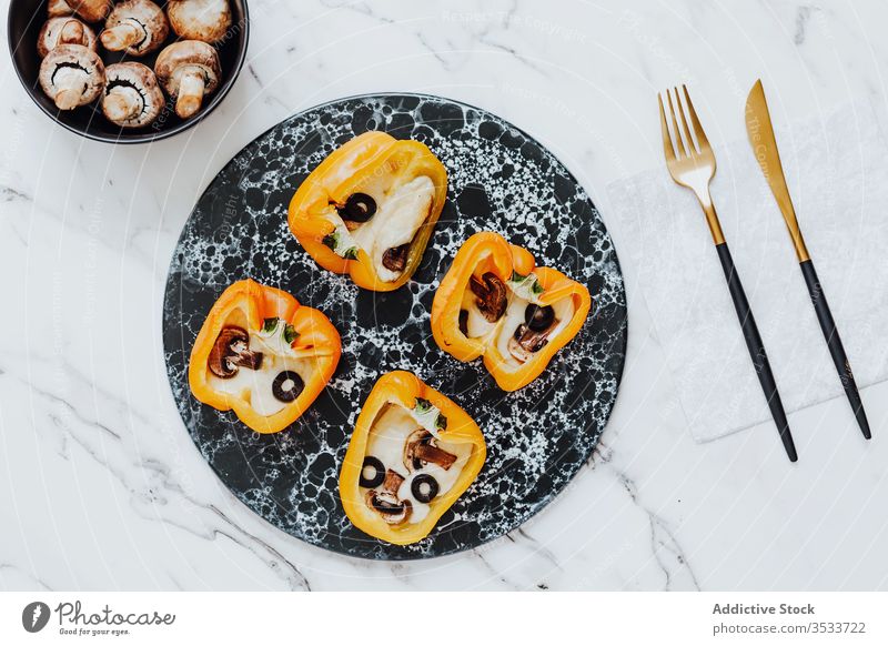 Bell peppers filled with roasted mushrooms and cheese with olives on marble plate food bell pepper snack bowl knife fork paprika meal natural culinary cuisine