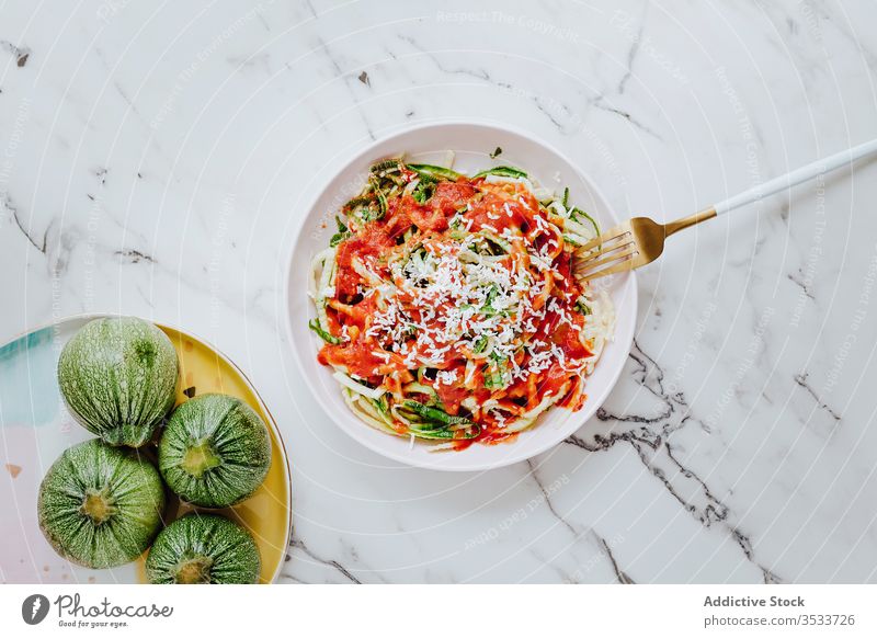 Homemade zucchini noodles with cheese and tomato sauce pasta healthy food veggie natural mix green culinary fork meal plate red lunch breakfast bowl dishware