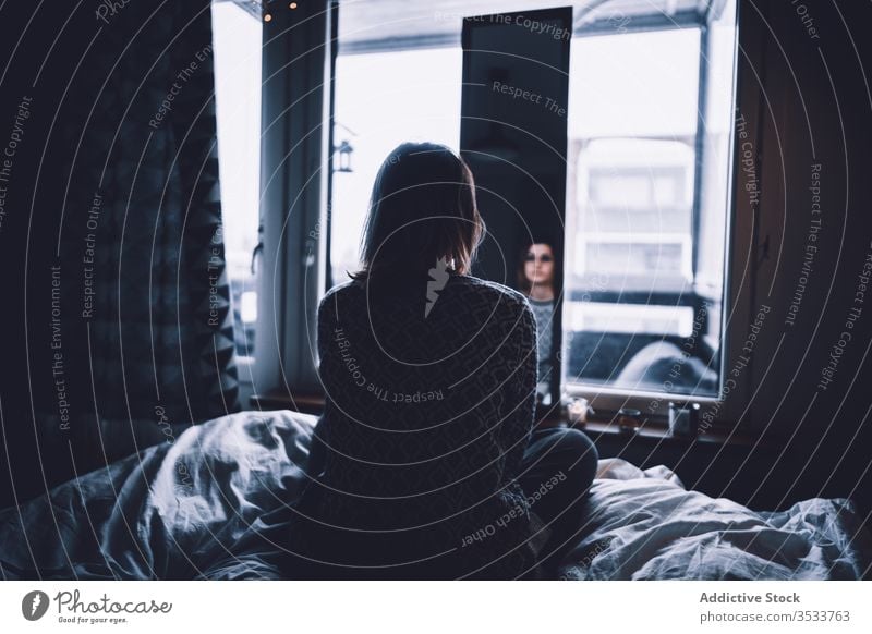 Lonely woman looking at mirror dark solitude bed depression window sit home female reflection apartment lonely silent melancholy shadow shade obscure flat