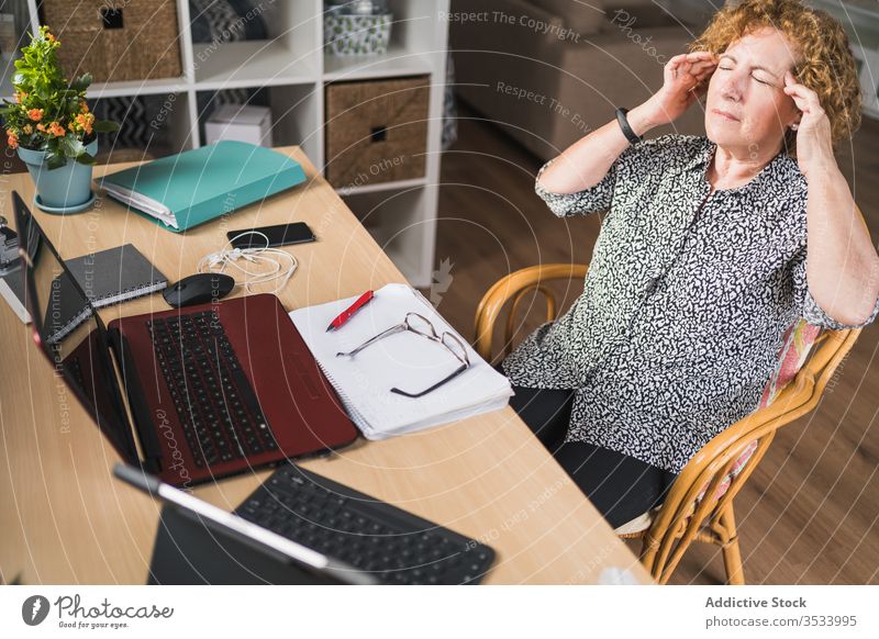 Female freelancer having break during work with documents and gadgets at home woman rest headache tired remote distance temple rub chair workplace laptop