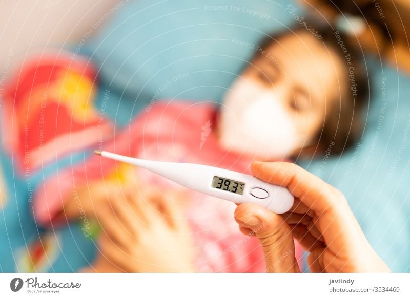 Mother measuring her toddler's temperature, protected by a mask. thermometer girl fever daughter caucasian people care illness flu cold sick unwell sickness