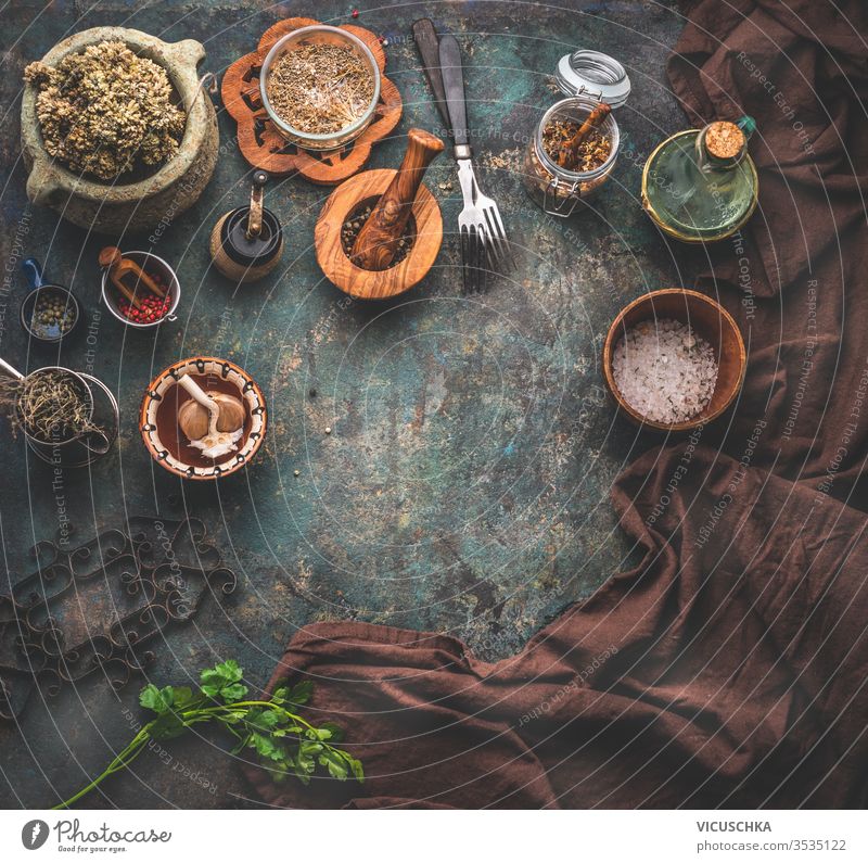 Rustic background with vintage kitchen utensils. Herbs and spices in wooden bowls, olives oil and napkin. Frame. Top view. rustic food background herbs frame