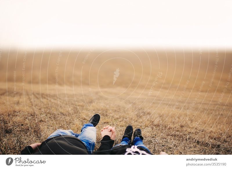 Couple in love man and woman lying in field holding hands. Concept of love. Autumn mood. Place for inscription people summer two together happy adult attractive