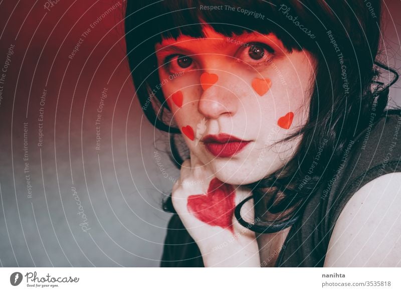 Artistic portrait of a young woman with red heart make up and covering by a red gradient ligth love beauty pretty face artistic valentines valentine's day