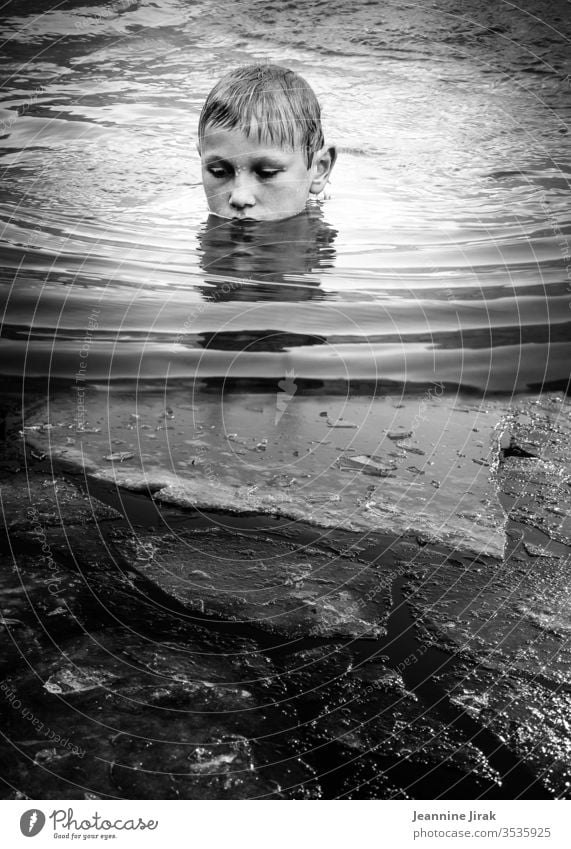 Boy bathes in icy water Boy (child) Water Lake Ice Swimming & Bathing Float in the water Waves Black & white photo Reflection vacation silent silence Monochrome