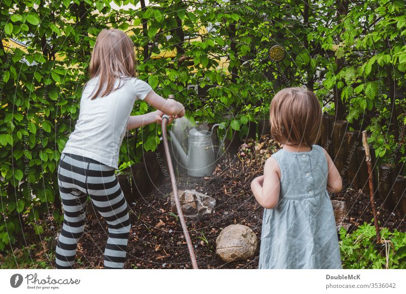 One girl waters the garden, the other watches children Colour photo Cast Attachment Affection Leisure and hobbies Garden Gardening Hedge muck about Engagement