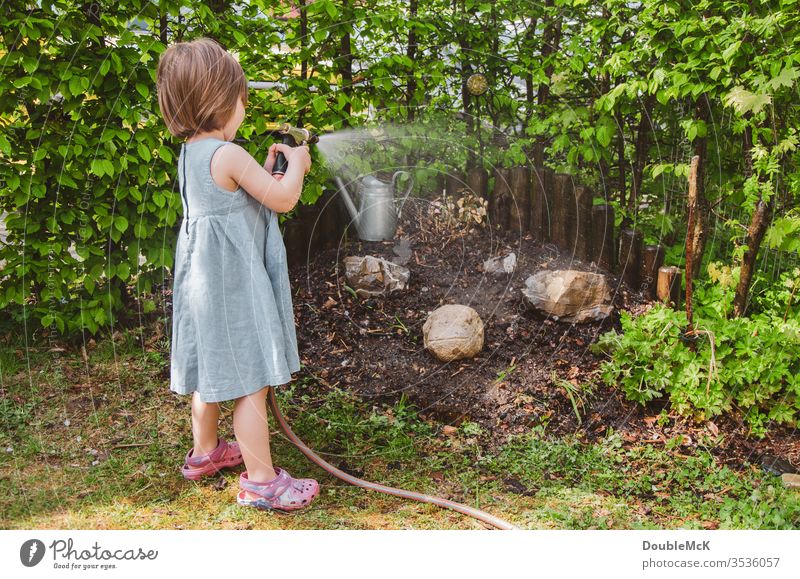 A girl waters the garden Colour photo Cast Leisure and hobbies Garden Gardening Hedge muck about Engagement engaged green Water hose Exterior shot Day Hose
