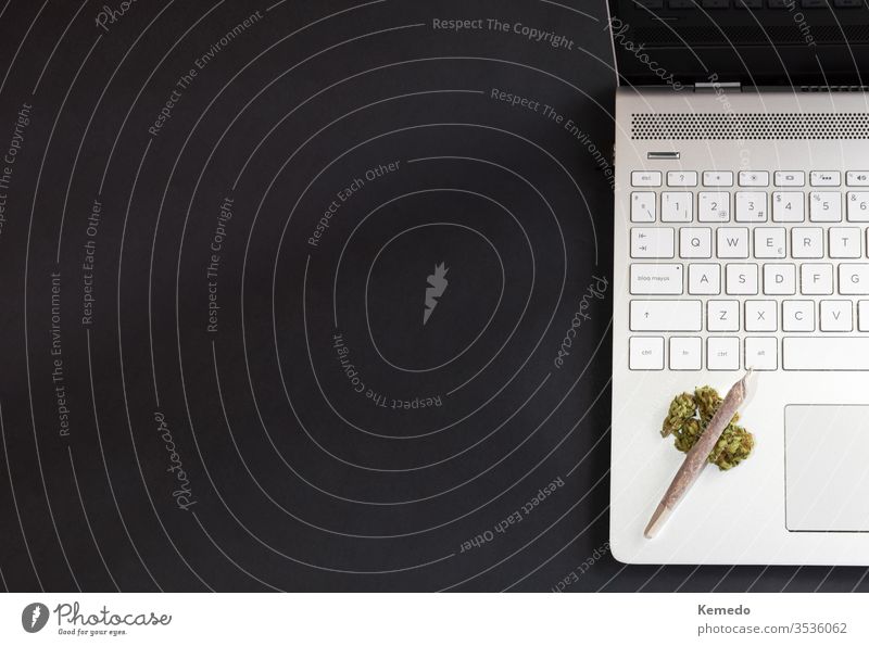 Marijuana and technology background. Cannabis buds and marijuana joint on laptop isolated on black background with copy space left. cannabis computer weed