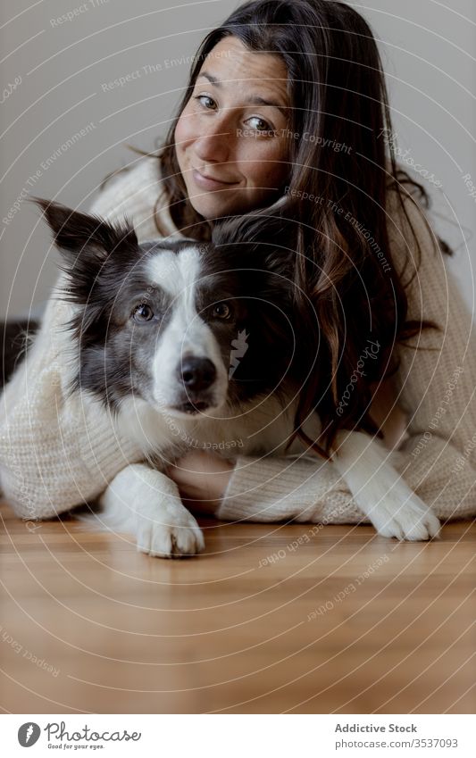 Happy woman embracing cute purebred gray white dog during rest on floor embrace hug care friendship pet adorable border collie together animal happy smile