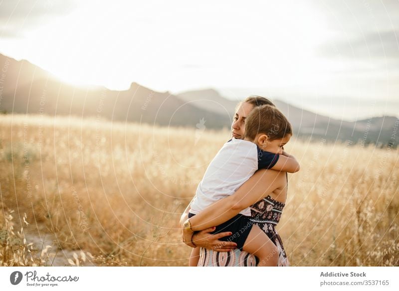 Mother and son resting in field mother sunset hug carry mountain love grass evening woman boy adult meadow sundown sky nature together countryside twilight dusk
