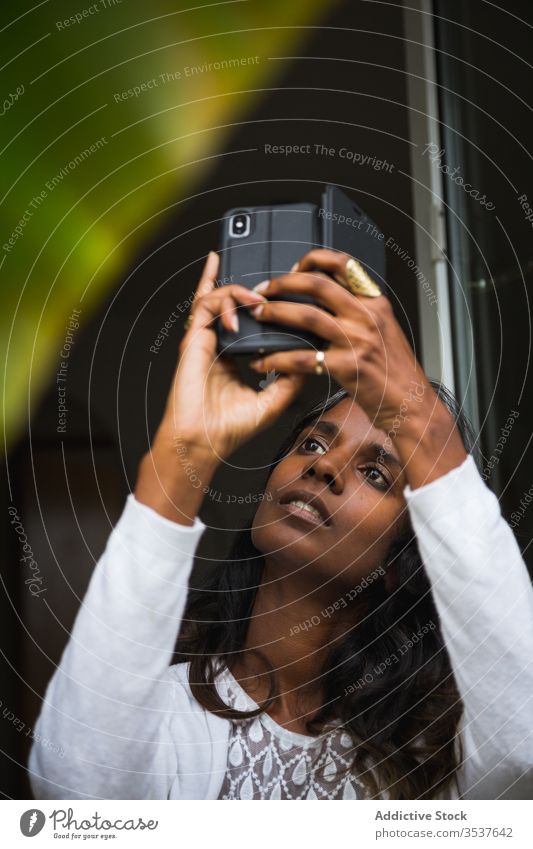 Concentrated Indian woman taking photo on smartphone take photo plant balcony concentrate camera mobile using female ethnic indian hindu focus serious