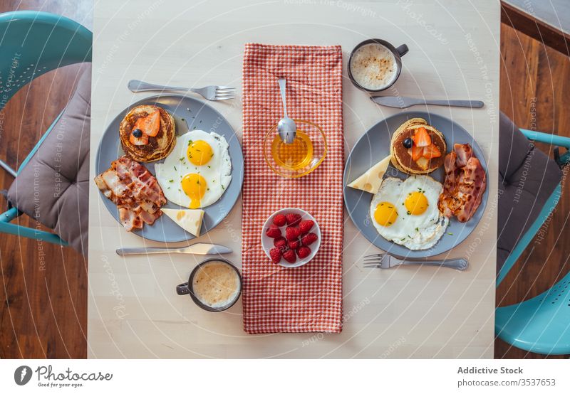 Delicious fried eggs with bacon and cheese for breakfast plate cupcakes strawberries black berries honey food serve meal pancake berry dish table nutrition