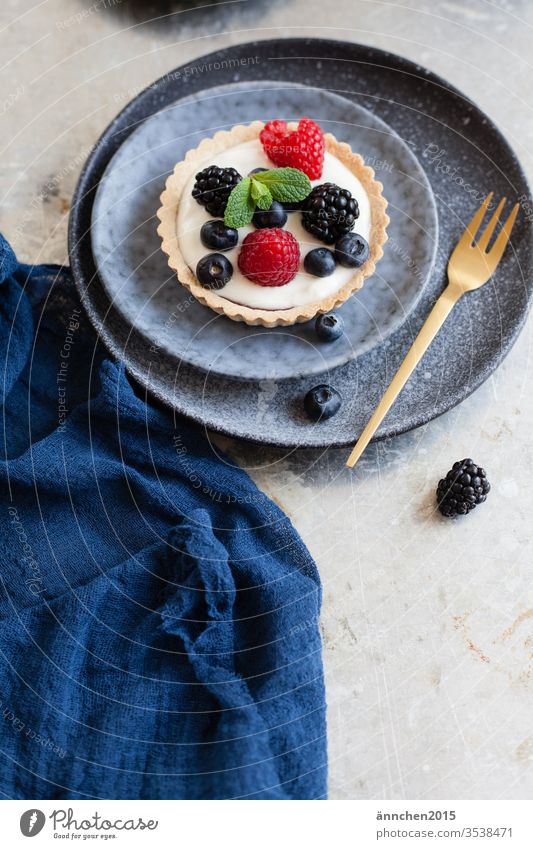 Berry tartlets on a dark blue plate with a golden fork Fork Plate Tartlet Nutrition Delicious Colour photo Interior shot Day Crockery Cutlery Deserted Appetite