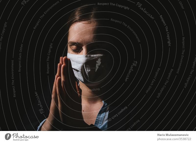 Religious woman with mask praying with hands for coronavirus covid-19 to end on black background adult caucasian christianity corona italy corona virus
