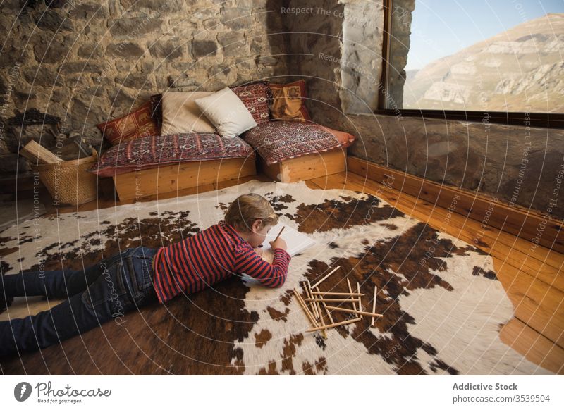 Kid drawing with colored pencils in sketchbook in living room boy house country cabin inspiration nature young carpet spain cantabria stone creative leisure