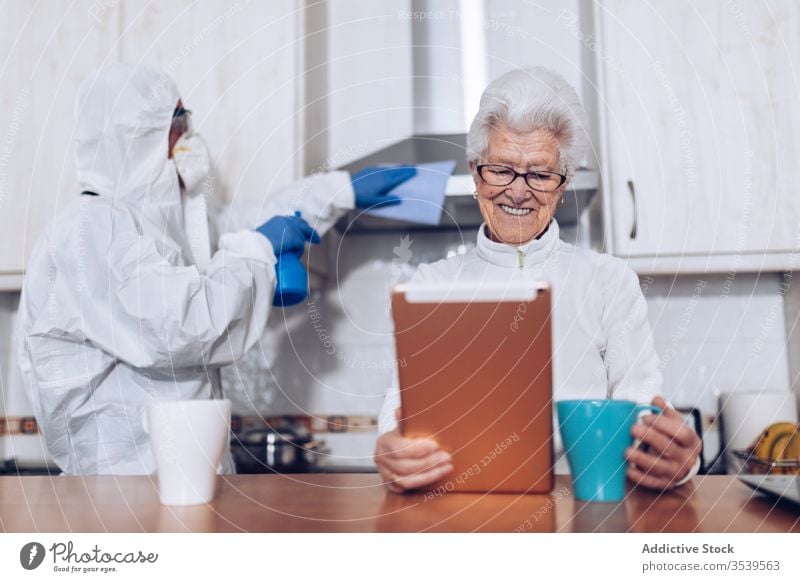 Home care employee helping senior client at home during quarantine coronavirus assistant visit show support kitchen cheerful happy book service social flu