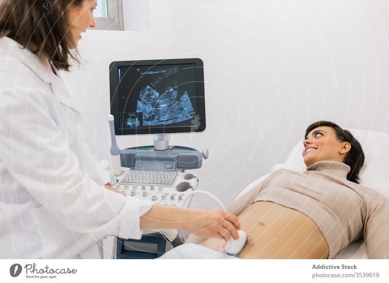 Female doctor making ultrasound scan to woman patient sonogram clinic fertile pregnancy women smile medicine belly practitioner happy pregnant work contemporary