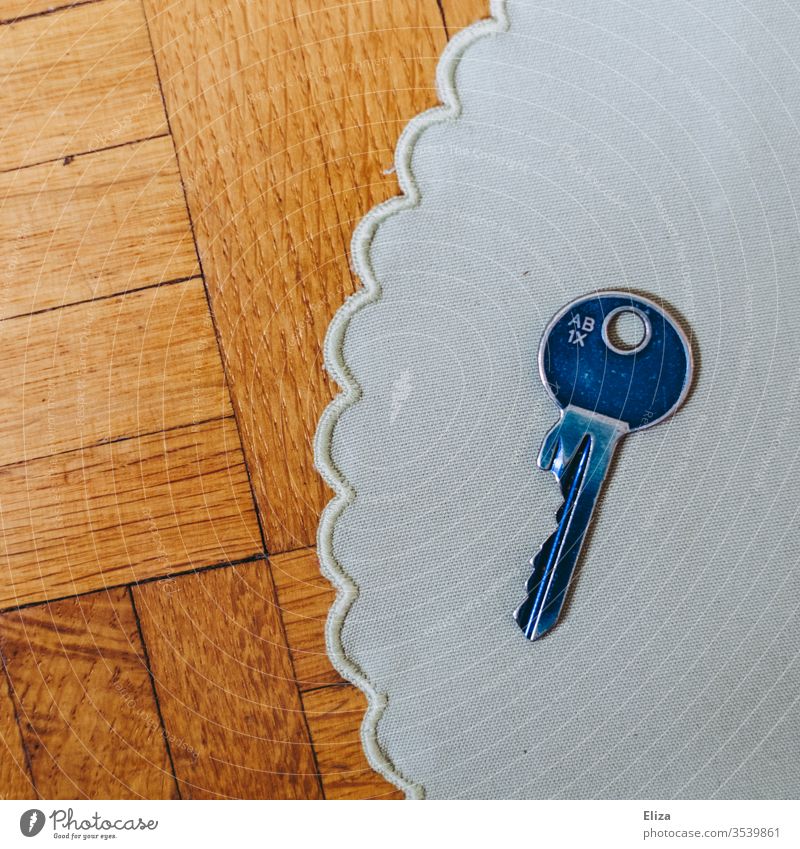 A blue key on a cloth cover on wood Key Blanket Blue dwell House key Safety Interior shot Day at home Flat (apartment)